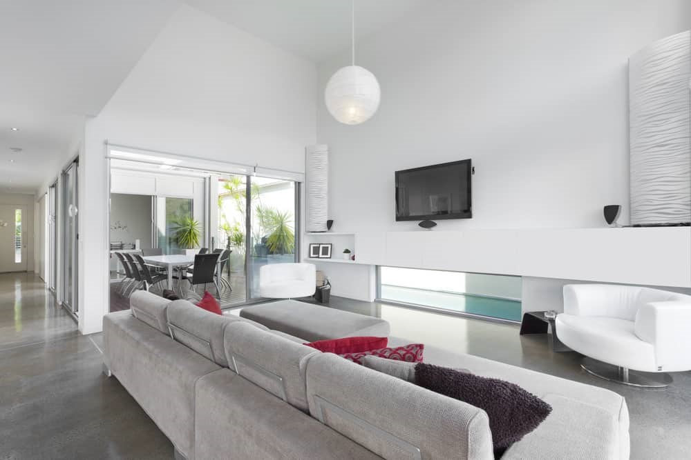 Phòng khách hiện đại tối giản với sofa góc xám và cửa kính lớn nhìn ra hồ bơi
