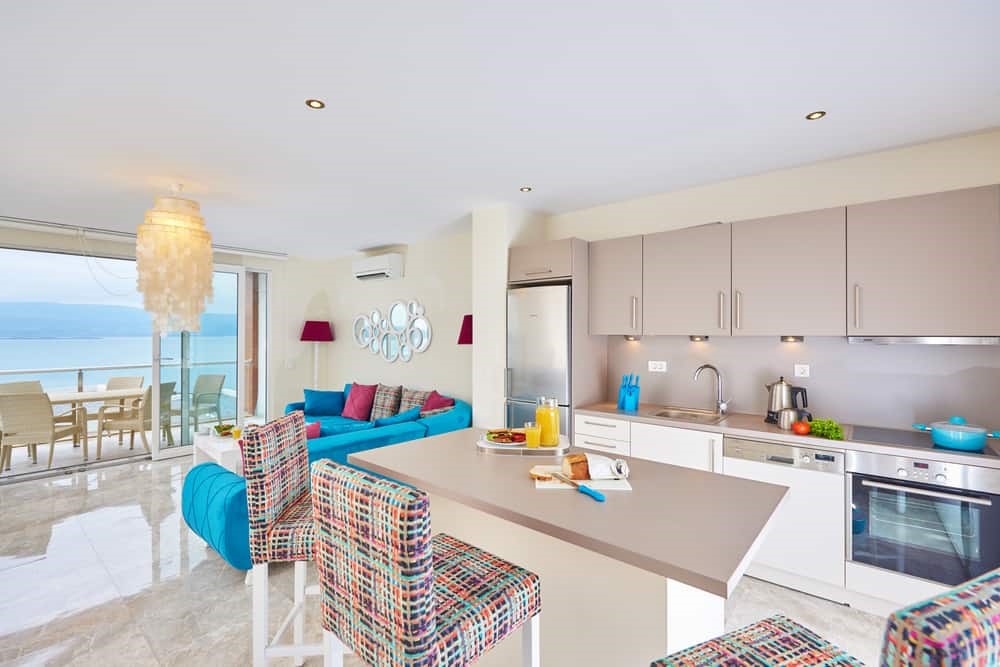 Căn hộ mở với bếp, bàn ăn và sofa xanh dương, nhìn ra ban công hướng biển